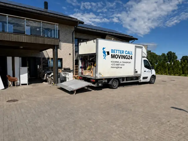 Машина Moving24 с опущенным гидробортом у современного частного дома, у входа стоит мебель